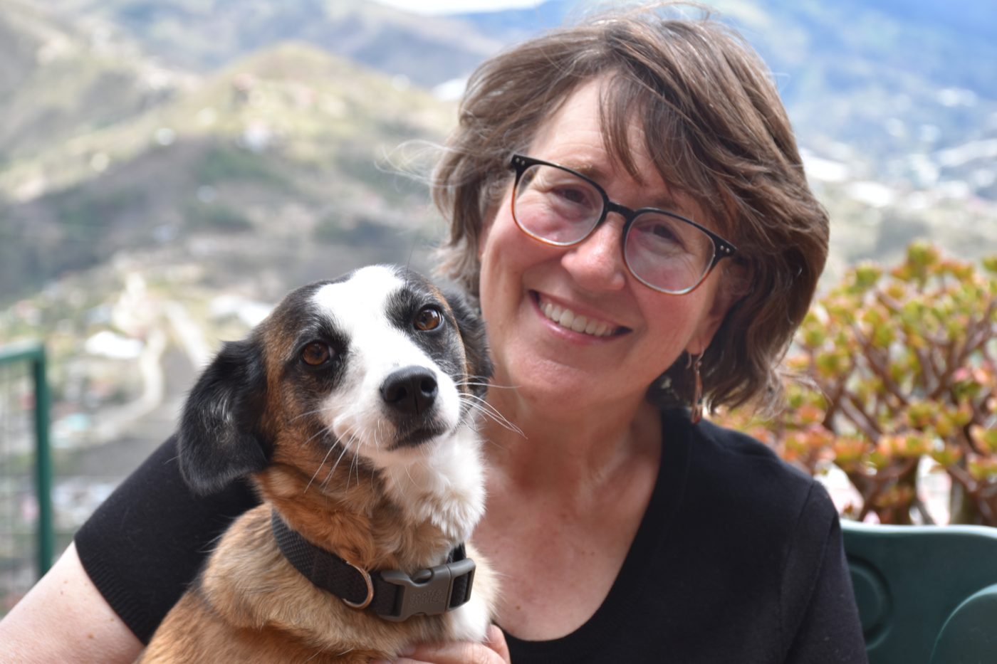 Lynne Klippel smiling with one of her rescue dogs, mountains behind them